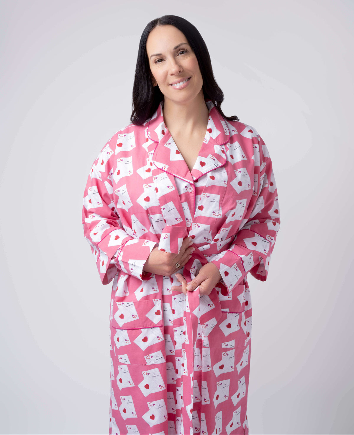 Woman wearing a pink robe with white patterns on a plain background