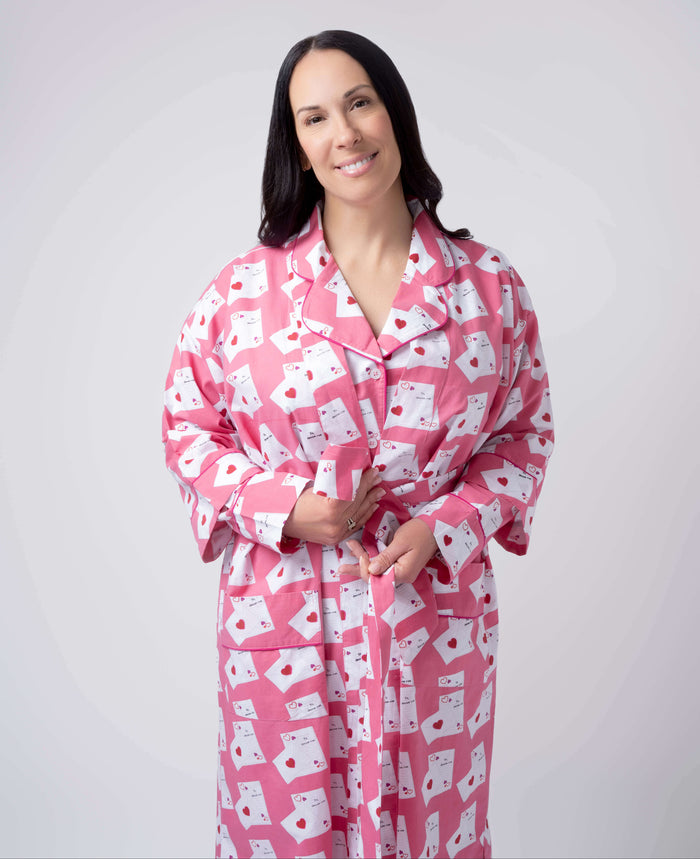 Woman wearing a pink robe with white patterns on a plain background