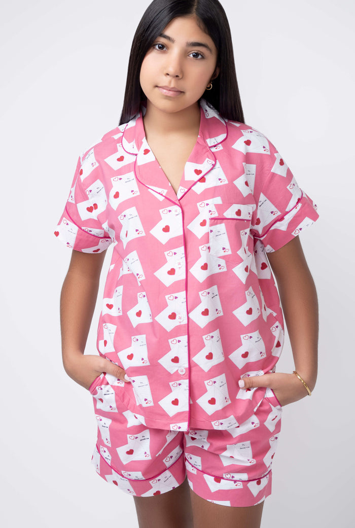 Person wearing a pink pajama set with white patterns on a white background
