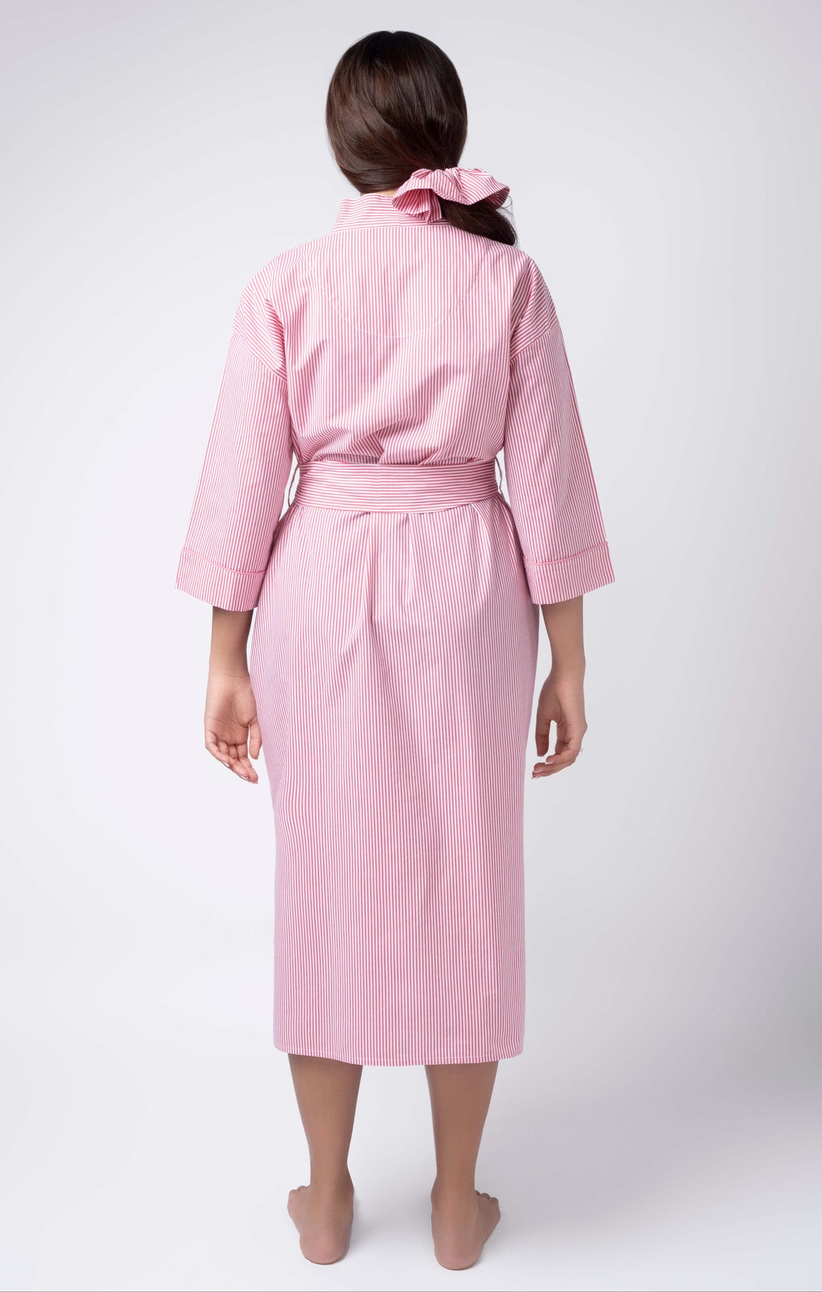 Person wearing a pink robe on a white background