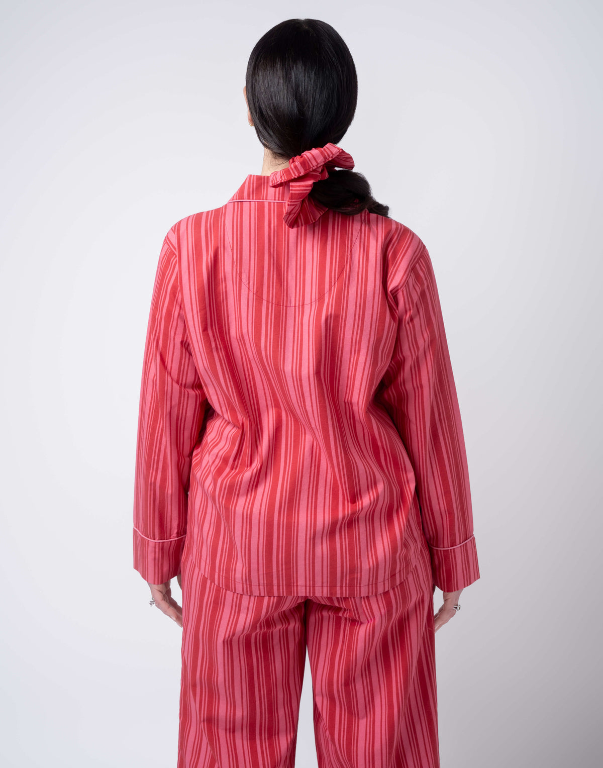 Person wearing a red striped pajama set from behind on a white background